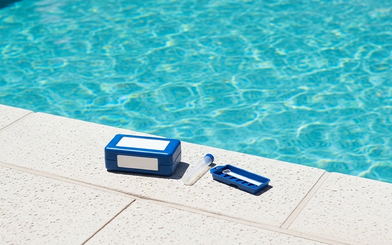 Pool test kit and sample tube beside clear water showing chemistry holding steady in Scottsdale, AZ