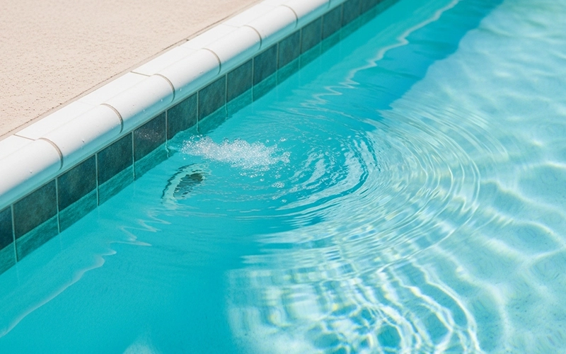 Clear pool water with visible return jet ripples showing strong circulation.