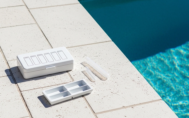 Pool test kit and sample tube beside clear water showing stable chemistry in Scottsdale, AZ