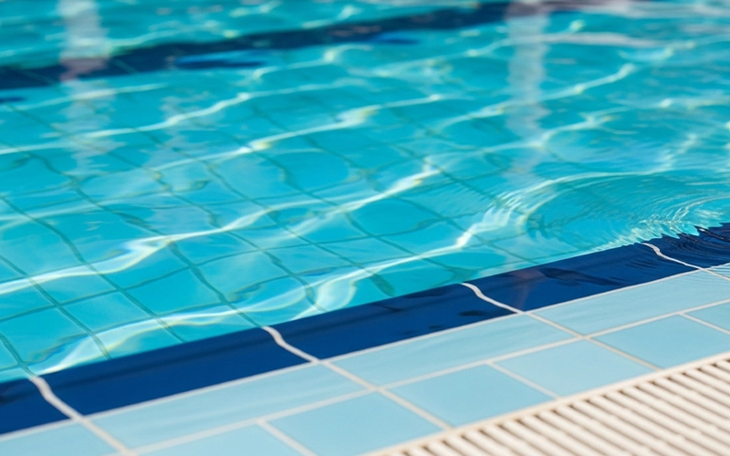Close-up of clear pool water showing sunlight patterns and clean tile edge.