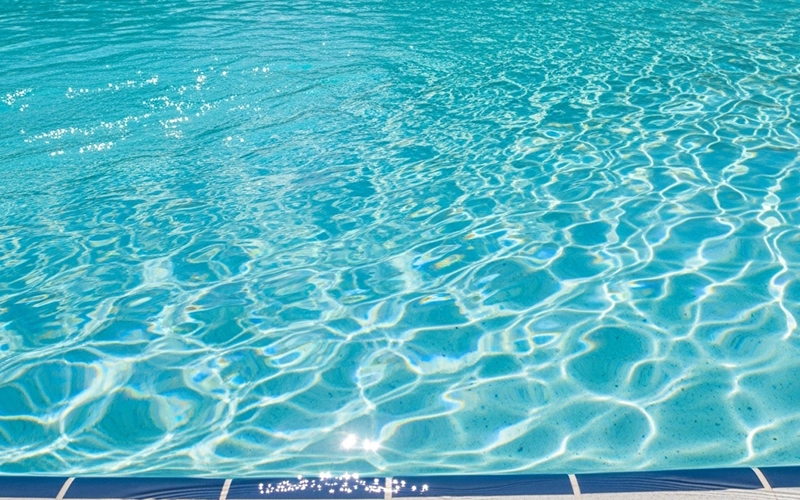 Crystal clear pool water in Arizona sun with soft ripples and bright blue reflections