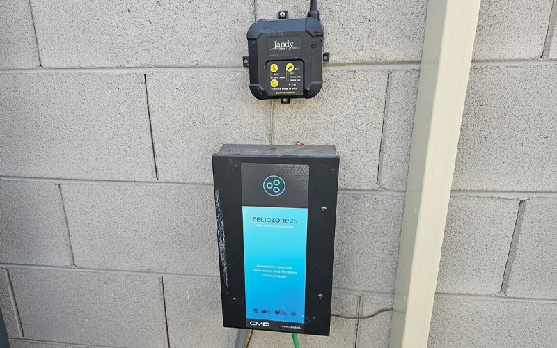 Wall-mounted Jandy Pro Series pool control unit installed above a DEL Ozone 25 APS ozone generator on a concrete block wall.