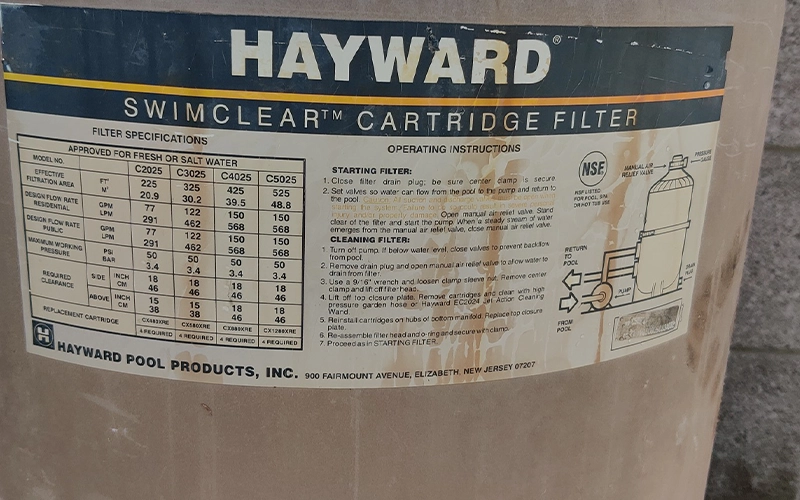 Close-up of the Hayward SwimClear cartridge filter specification label on a residential pool filtration system.