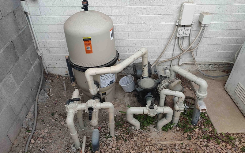 Residential pool equipment pad featuring a Pentair Clean & Clear Plus cartridge filter, pool pump, and plumbing connections installed beside a home.