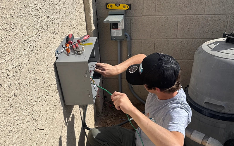 Pool technician inspecting electrical controls and equipment during pool equipment maintenance
