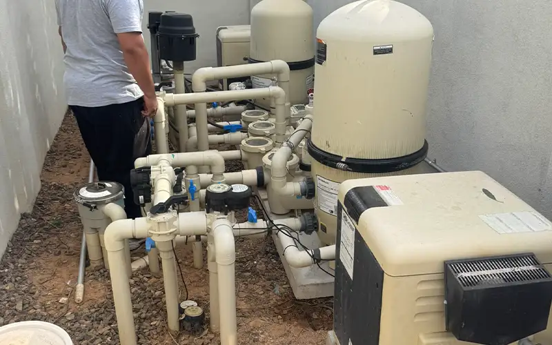 Pool technician inspecting complex pool equipment system to prevent repair issues from turning into larger problems