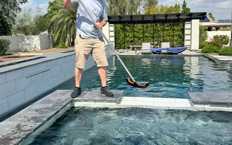 Pool technician performing detailed cleaning and maintenance to keep a residential swimming pool stable in Arizona