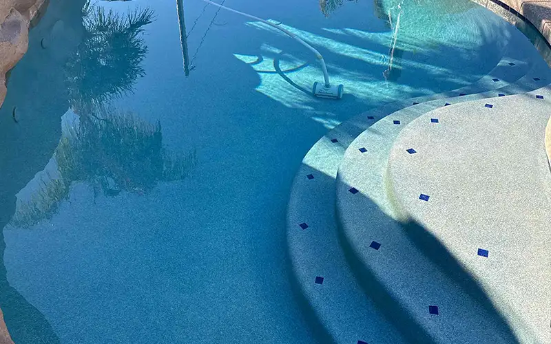 Residential pool with clear water and vacuum equipment showing proper circulation and routine pool maintenance in Arizona