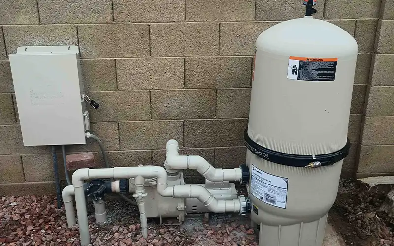 Pool equipment pad with a Pentair filter tank, circulation pump, pressure gauge, control box, and PVC plumbing