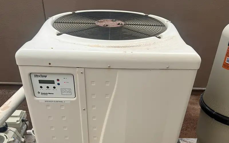 White Pentair UltraTemp pool heat pump installed beside pool filtration equipment