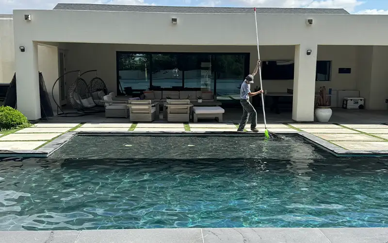 Pool technician providing detail-focused weekly pool cleaning service at a residential property