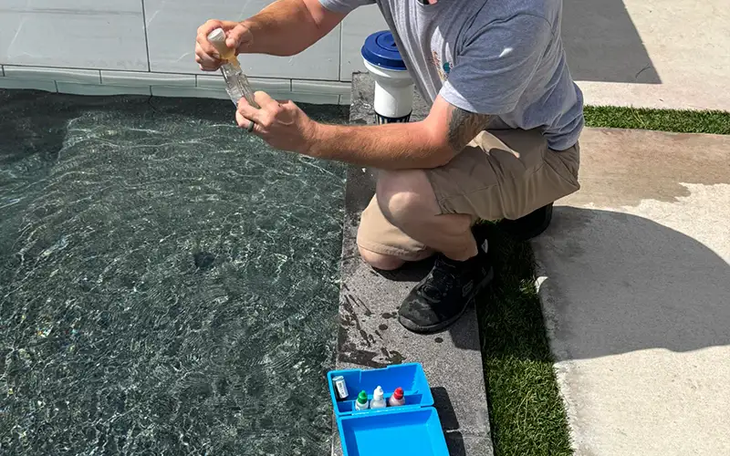 Pool technician testing water with a chemical testing kit beside a swimming pool