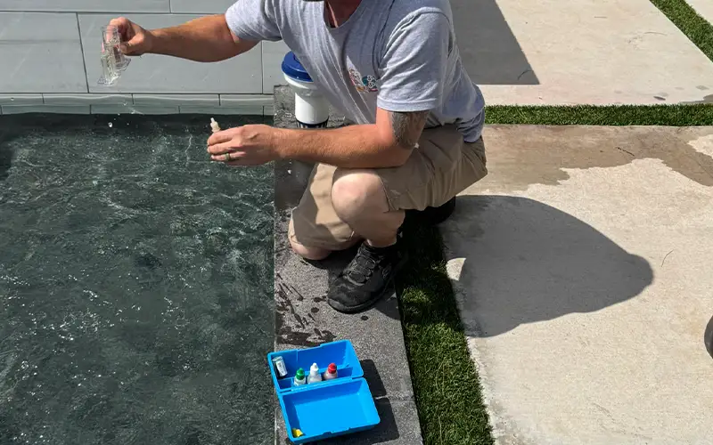 Pool technician testing water chemistry to maintain balanced and clean swimming pool water